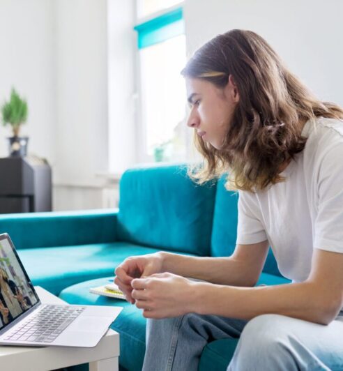 Individual online lesson, teenage boy studying at home with laptop Individual online lesson, teenage boy sitting at home with laptop, studying using remote video consultation, female teacher mentor on computer screen. E-education, technology in teaching, adolescence