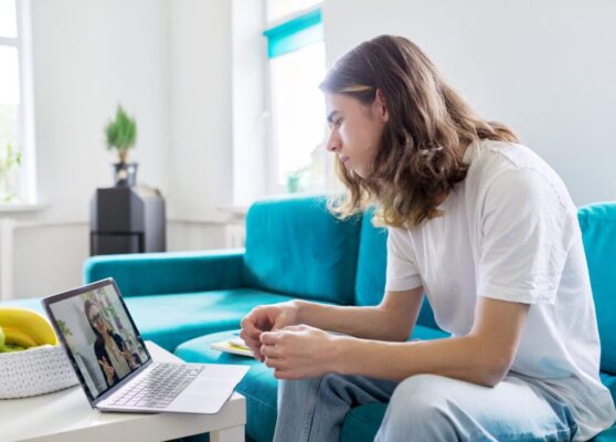 Individual online lesson, teenage boy sitting at home with laptop, studying using remote video consultation, female teacher mentor on computer screen. E-education, technology in teaching, adolescence
