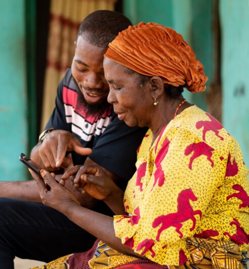 a young african man assisting an elderly woman using her phone young african man assisting an elderly woman using her phone