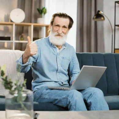 Handsome mature gentleman sitting at a desk, using a laptop for a video call