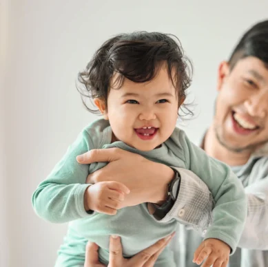 Young father smiling happily as he plays with his child, making parenting look easy