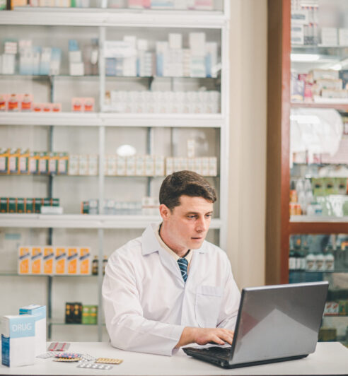 Male pharmacist checking, analyzing or Checks Inventory of Medic Male pharmacist checking, analyzing or Checks Inventory of Medicine, Drugs, Vitamins and checking prescription drugs for patients in modern pharmacy