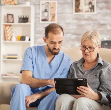 Nurse showing something on a tablet to an elderly woman at home
